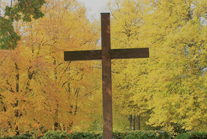 großes Holzkreuz vor Herbstbäumen